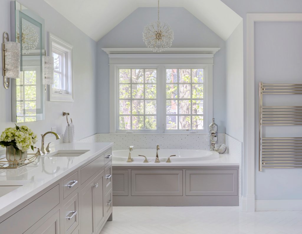 In this master bathroom, soothing blue gray paint is paired with soft gray vanities for a serene spa look. Courtesy of Woodharbor Custom Cabinets. 